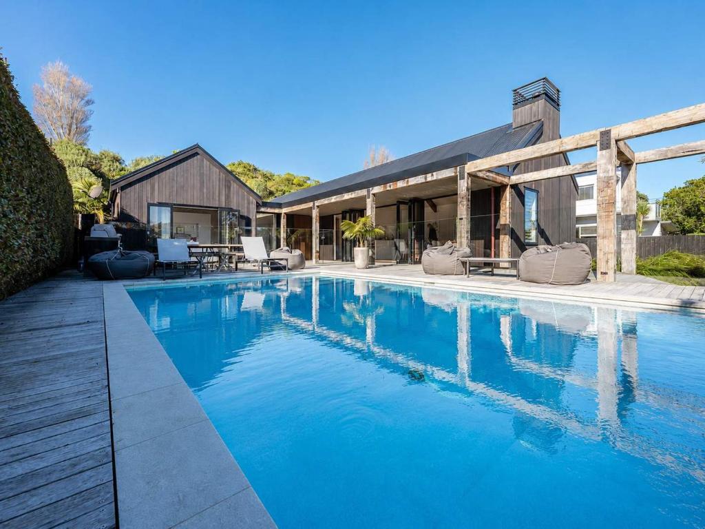a swimming pool in front of a house at Blackpool Boathouse - Stay Waiheke in Oneroa