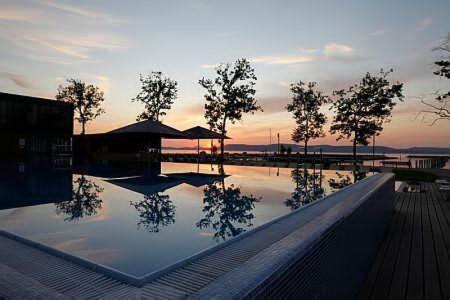 a reflection of trees in a pool of water at sunset at Balino C1 in Balatonlelle