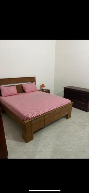 a wooden bed with pink pillows in a bedroom at Belle villa in Toubab Dialaw