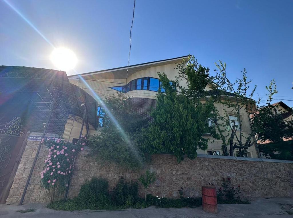 a house with the sun shining behind a wall at Aigul Hostel in Shymkent