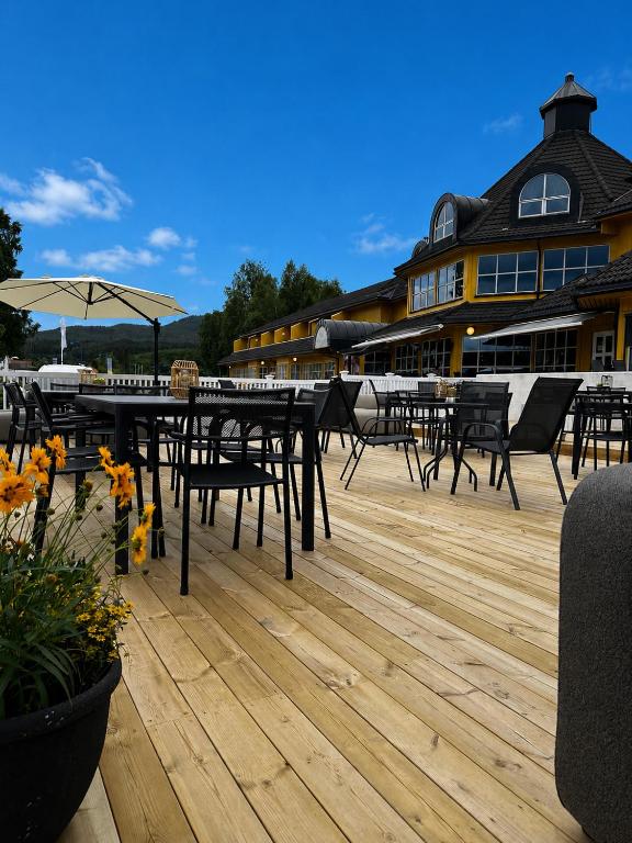 a deck with tables and chairs and a building at Grong Hotell in Grong