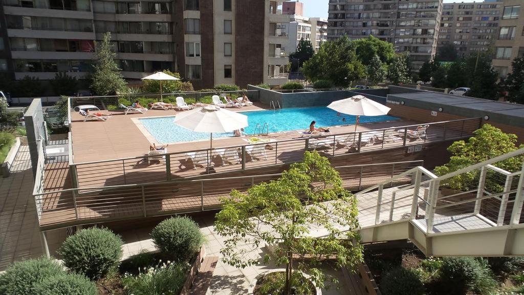 una piscina con sombrillas y gente sentada a su alrededor en M Montt Las Condes, en Santiago