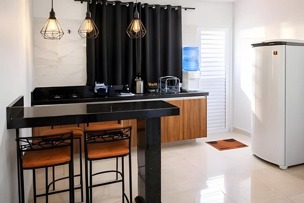 a kitchen with a black counter and a refrigerator at Loft 2 com Ar e Garagem até 6 Pessoas Rede Urbana in Indaiatuba