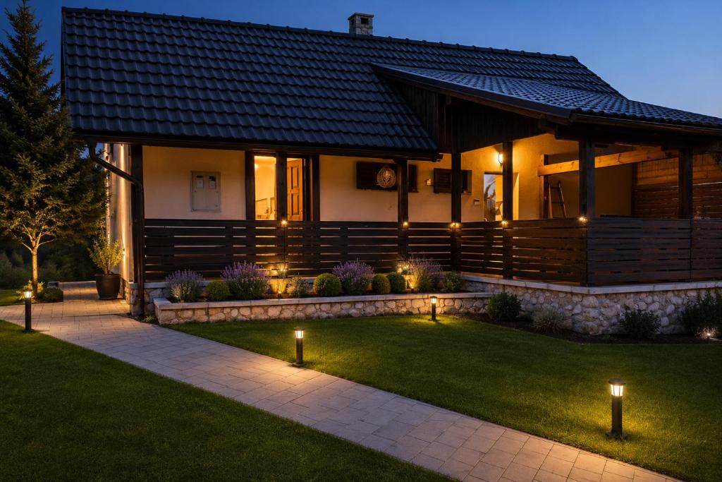 a house with lights in the yard at night at Guest House Lisina in Poljanak