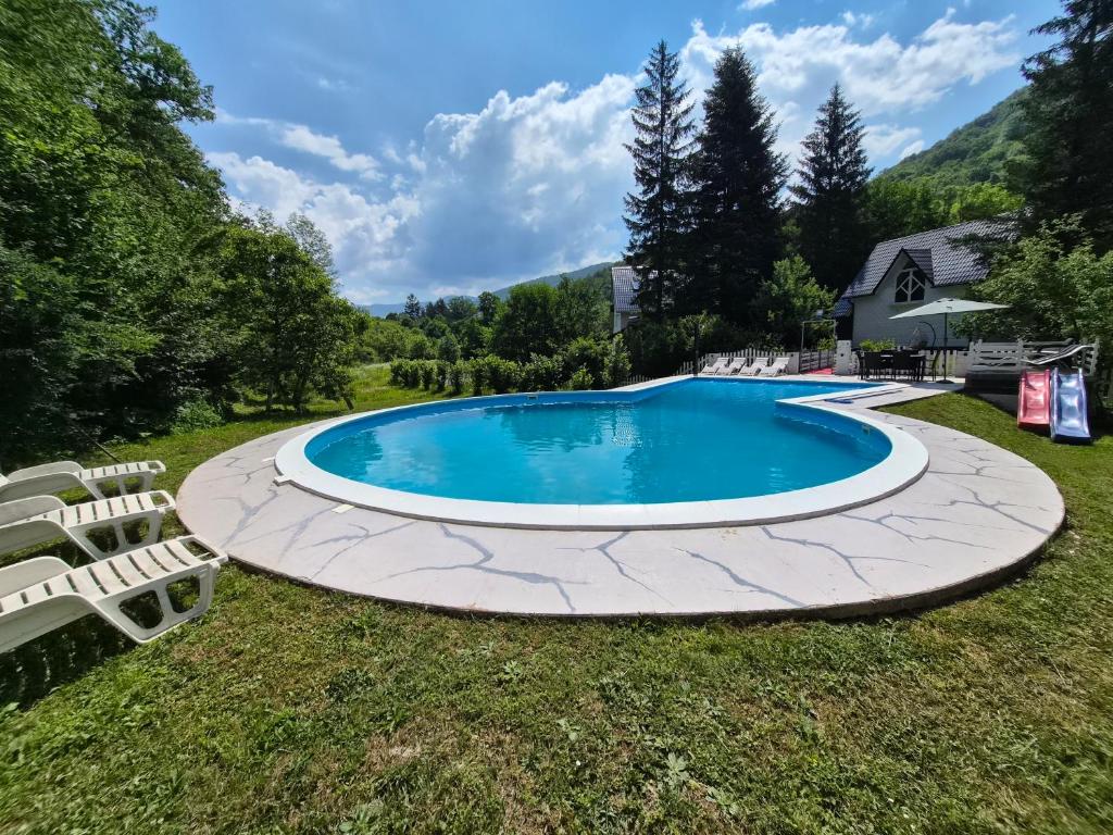a swimming pool with two chairs and a house at Vila Dolina Izvora in Sarajevo