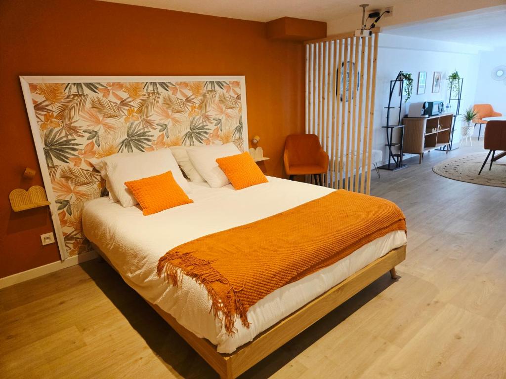 a bedroom with a large bed with an orange blanket at La Parenthèse du Buisson Bailly - Jacuzzi, Détente et Bien être près de Provins in Choisy-en-Brie