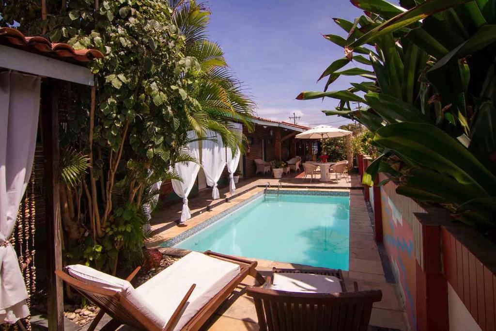 a swimming pool in a yard with chairs and trees at Pousada Le Baron in Praia do Frances