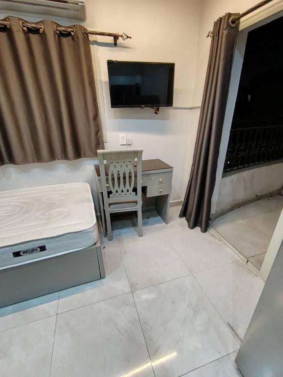 a room with a bed and a tv and a chair at Abu safa home in Al Ghuşnah