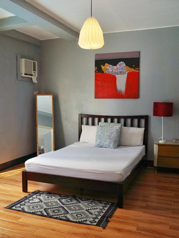 a bedroom with a white bed with a red painting at Apartment with Kitchen Walking Distance to Station Two in Boracay