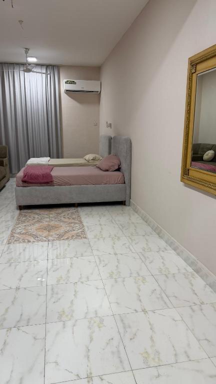 a bedroom with a bed and a mirror on the wall at Cozy rooms in Mirbāţ
