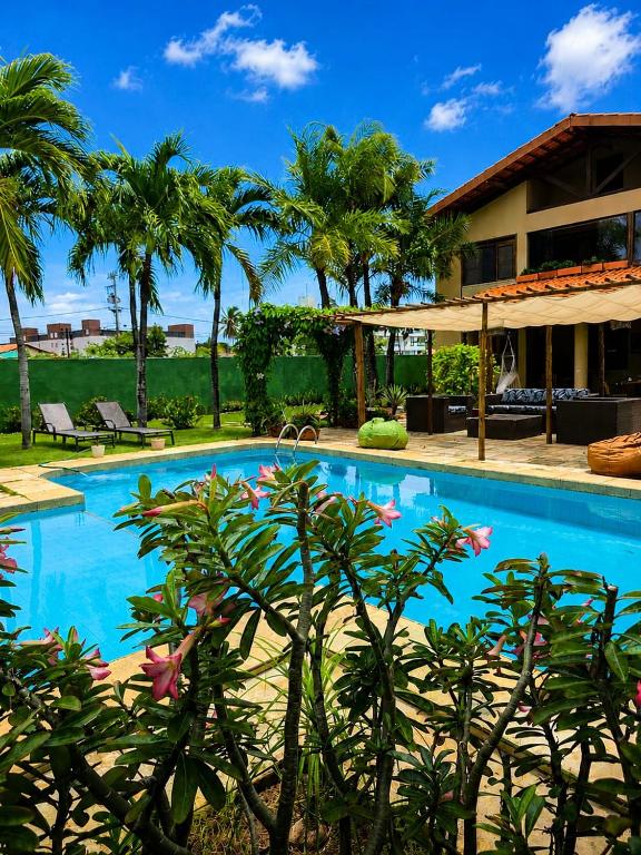 a swimming pool in front of a house with palm trees at Alisios Kite Lodge in Cumbuco