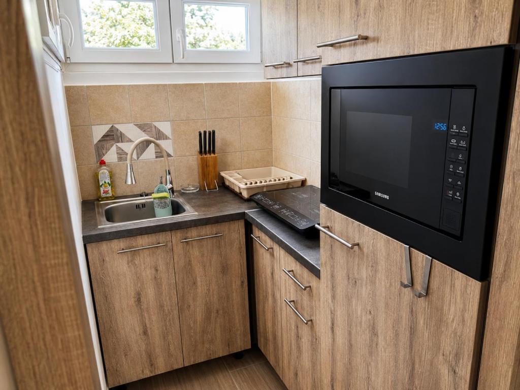 a small kitchen with a microwave and a sink at Gunilak in Dombóvár