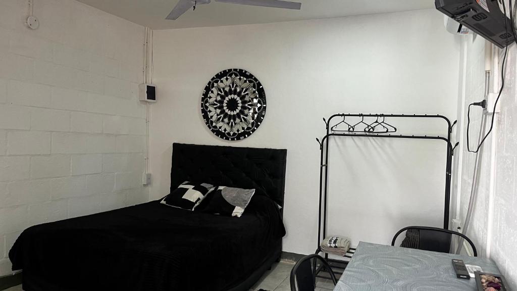 a bedroom with a black bed and a clock on the wall at 3 Acogedor y confortable monoambiente in Santiago del Estero