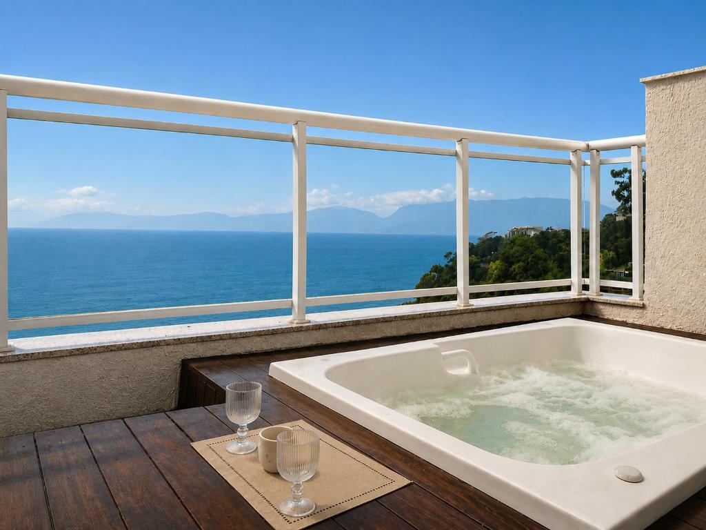 a bath tub sitting on a balcony with a view of the ocean at Porto Real Resort Suítes in Mangaratiba