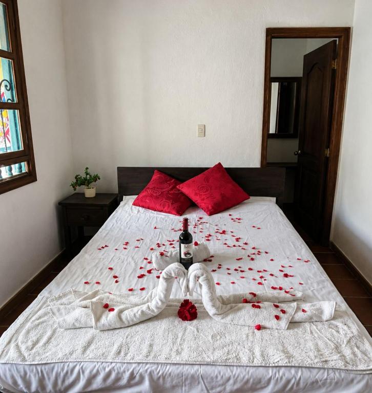 a bed with red roses and a bottle of wine on it at Hotel Lancers in Paipa