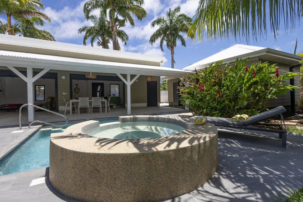 a backyard with a pool and a house at Majesty Palm Hôtel in Saint-François