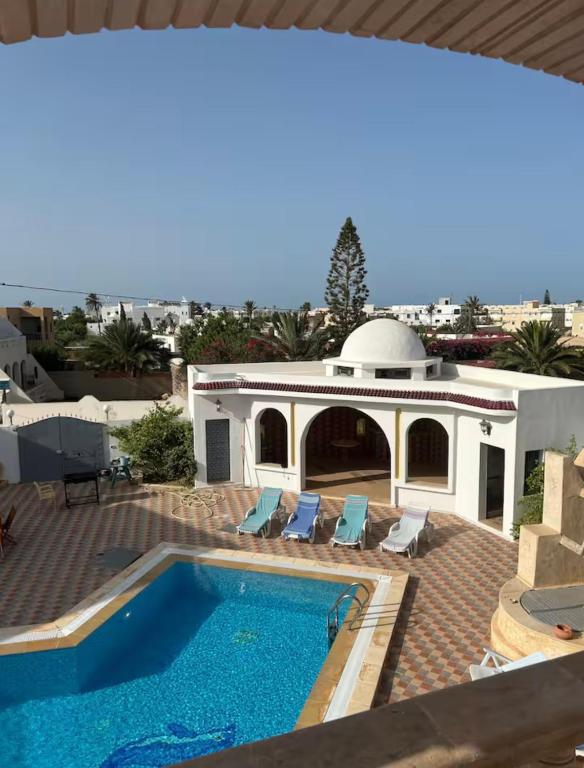 a villa with a swimming pool and a house at Résidence Djerba Oasis in Mezraya