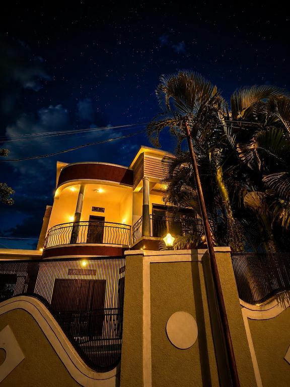 a house with a palm tree in front of it at EDEN PALACE KIGALI AIRPORT AND APARTMENTs in Kigali