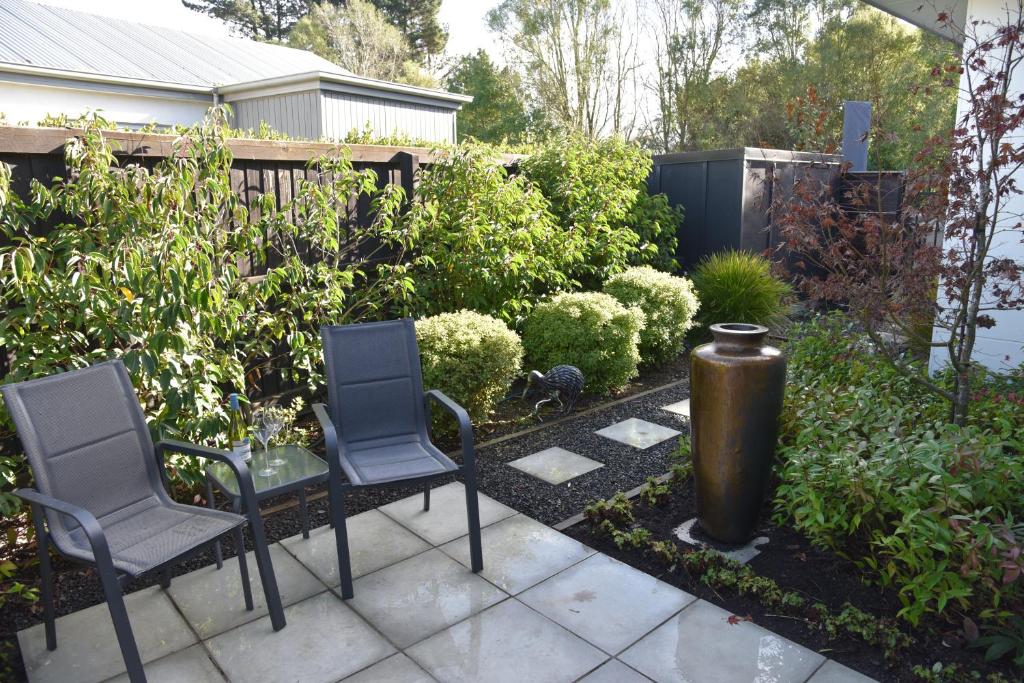 a garden with two chairs and a trash can at Rojan's Roost in Christchurch