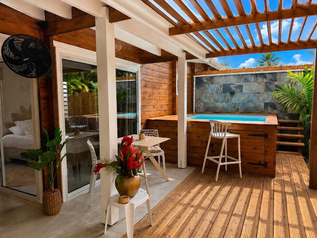 a deck with a pool and a table and chairs at Filao Cottage Bungalow avec Piscine Privée Proche plages in Sainte-Rose