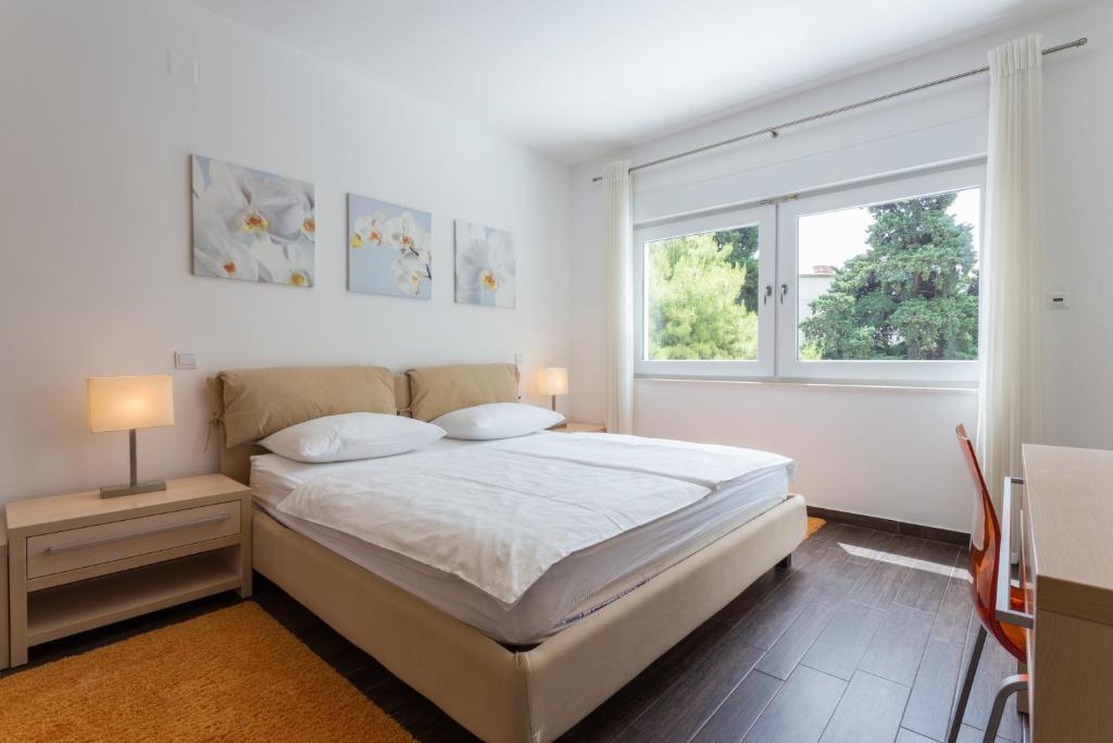 a white bedroom with a bed and a window at Apartments Villa Alba in Dubrovnik