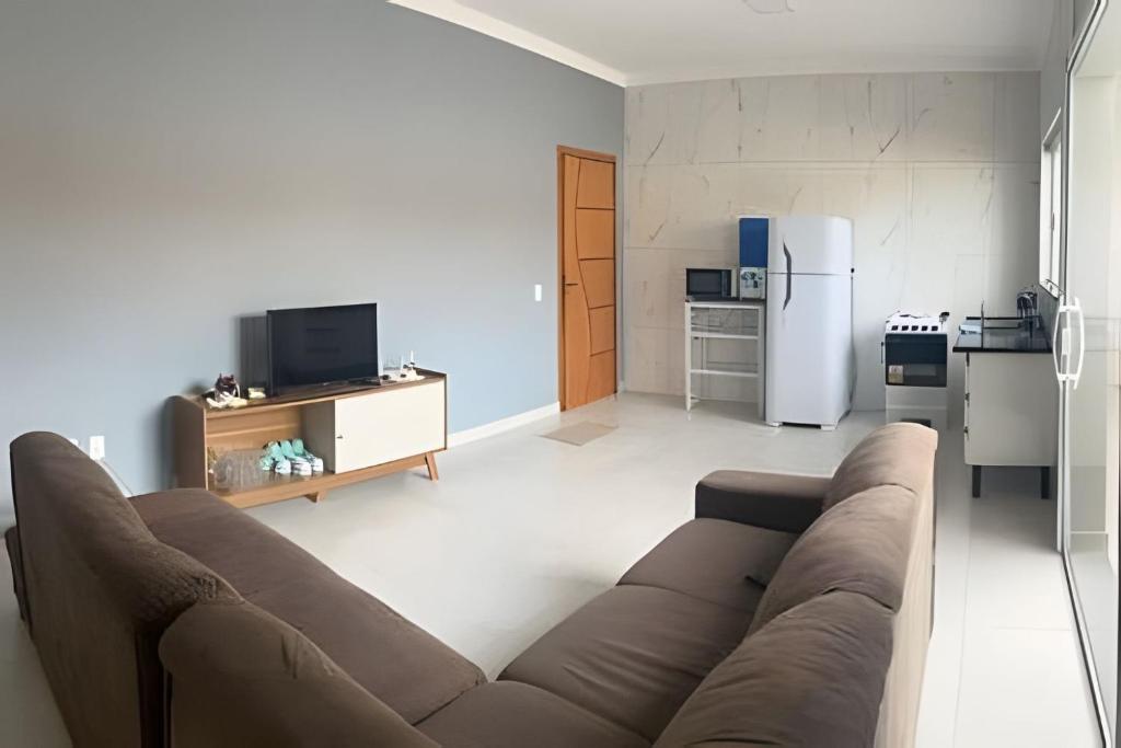 a living room with a couch and a kitchen at Apartamento 2 quartos c/ ar-condicionado e garagem in Indaiatuba