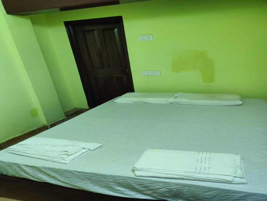 two beds in a green room with towels on them at Spot On V GUST IN in Tenāli