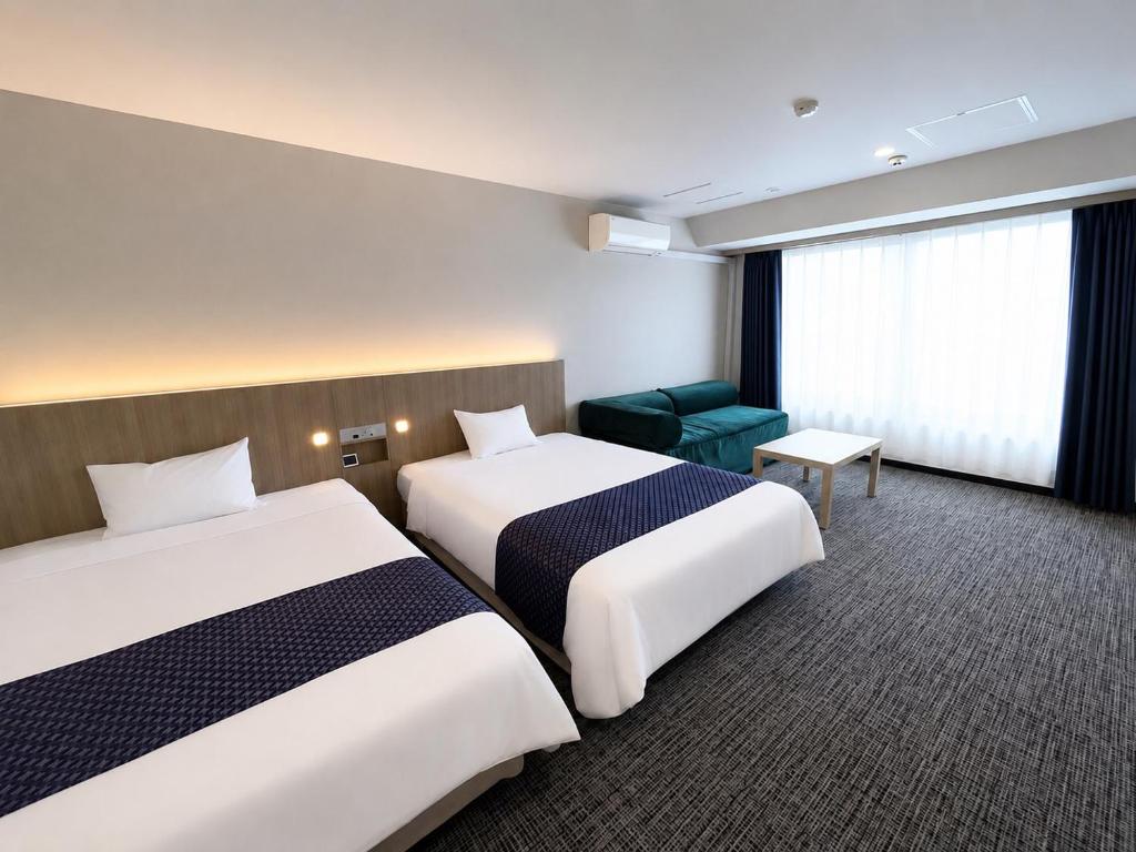 a hotel room with two beds and a green chair at Hotel 21 in Kusatsu