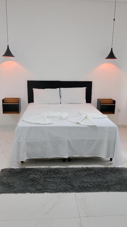 a bedroom with a large white bed with white sheets at Suíte Lençóis - Quarto amplo com Cozinha Integrada in Lençóis