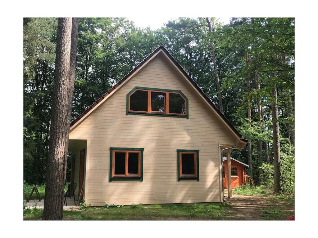 a small white house in the middle of a forest at Forest park at Roofensee in Stechlin