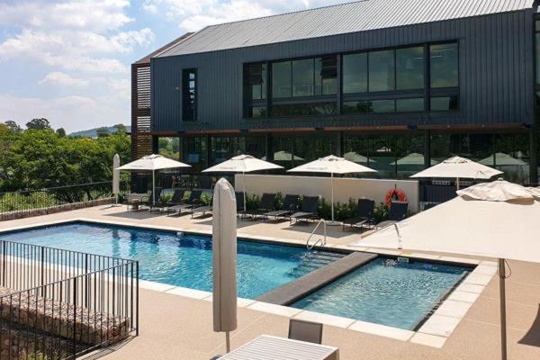 a large building with a swimming pool with umbrellas at Luxury Apartment Overlooking the River in Midrand