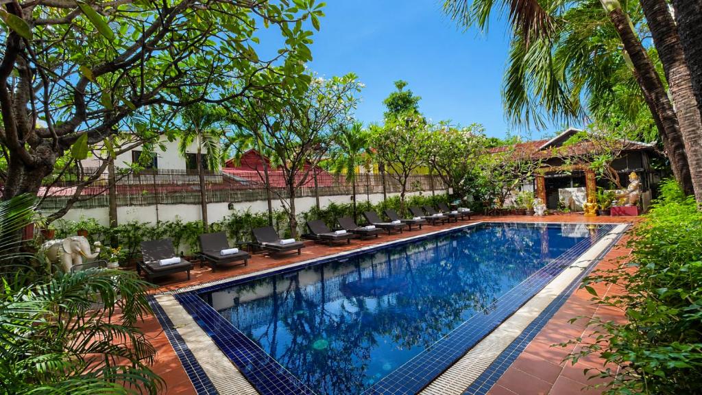 a swimming pool with lounge chairs next to a house at Harmony Indochine d'Angkor in Siem Reap