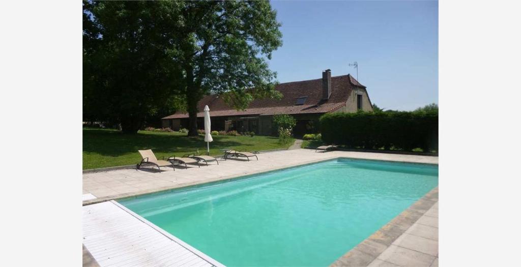 uma piscina com duas cadeiras e uma casa em La ferme d'aristide em Saillenard