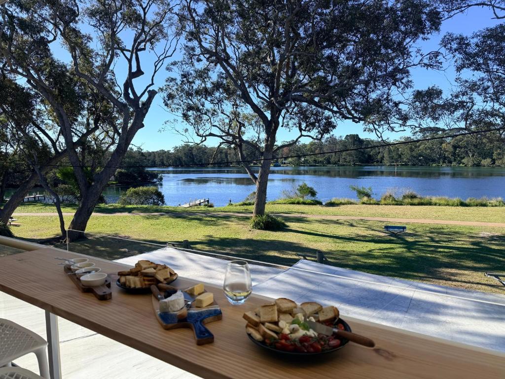 a table with a bowl of bread and a glass of wine at Sussex View - Waterfront Couples Retreat in Sussex Inlet in Sussex Inlet
