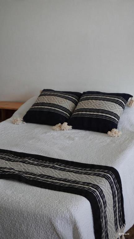 a bed with black and white sheets and pillows at Hotel del Pueblo in Teotitlán del Valle