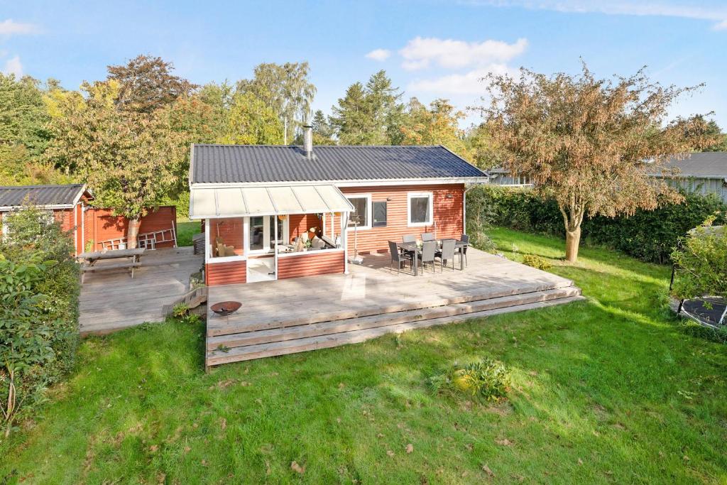 a log cabin with a deck in a yard at Cozy Cottage At Tuse Næs In Holbæk in Holbæk