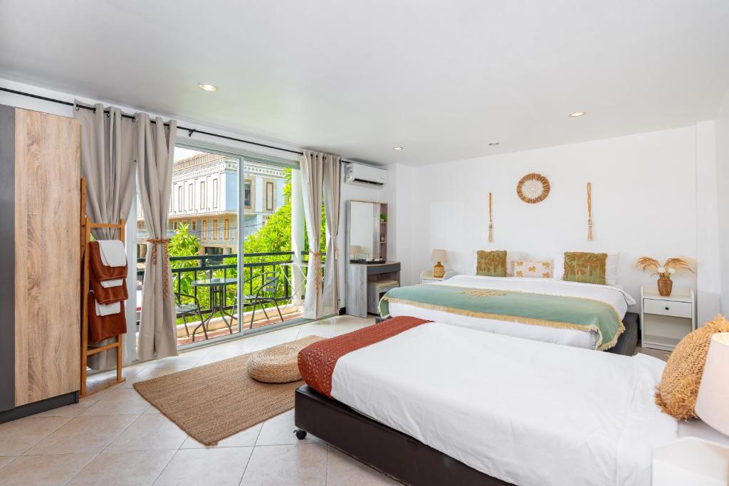 two beds in a bedroom with a balcony at Kata Station Boutique Hotel, Kata Beach in Kata Beach