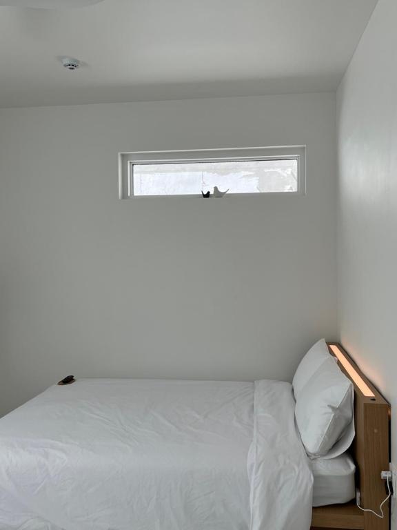 a white bedroom with a bed and a window at 까사뚜아 Casa Tua in Sokcho