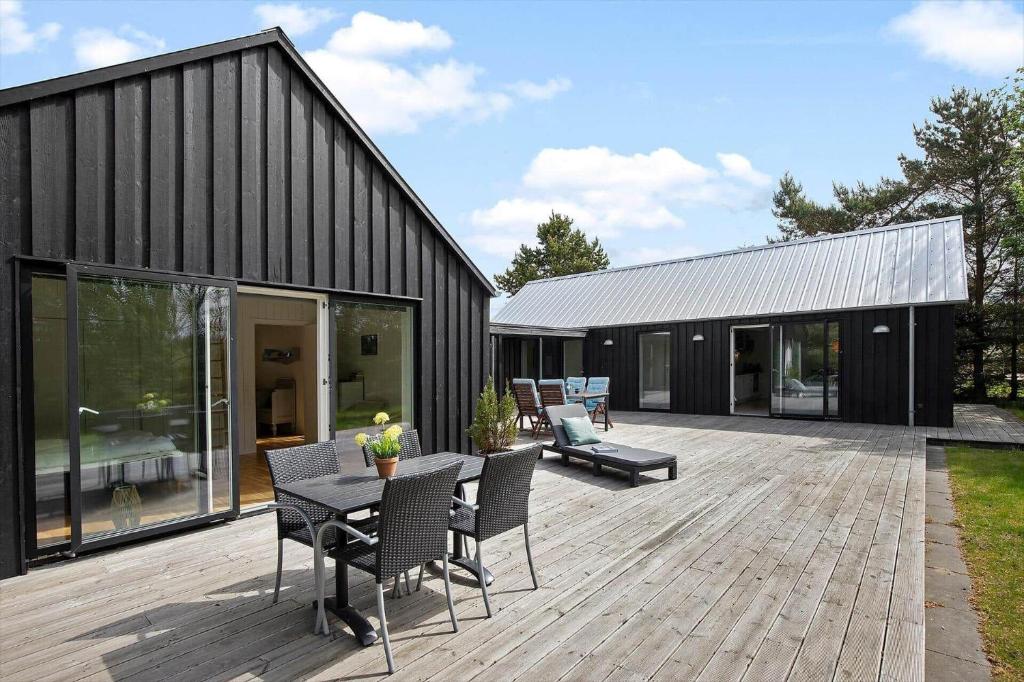 a black house with a wooden deck with a table and chairs at 8574-Grenaa-Annavej-13 in Gjerrild