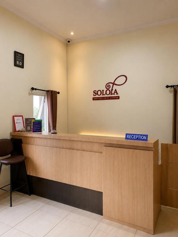a reception desk with a sign on the wall at Solota Boutique Hotel Syariah in Bonorejo