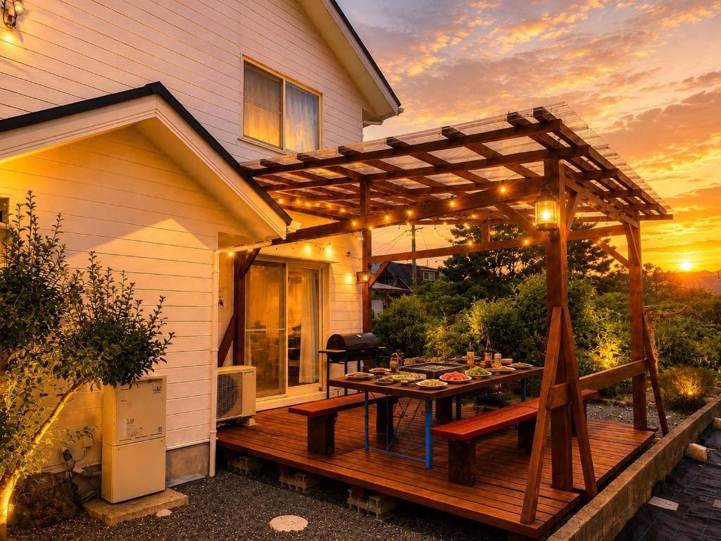 a wooden deck with a table and a pergola at Biwa 広々テラス bbq 無料駐車場 湖まで徒歩3分 in Takashima