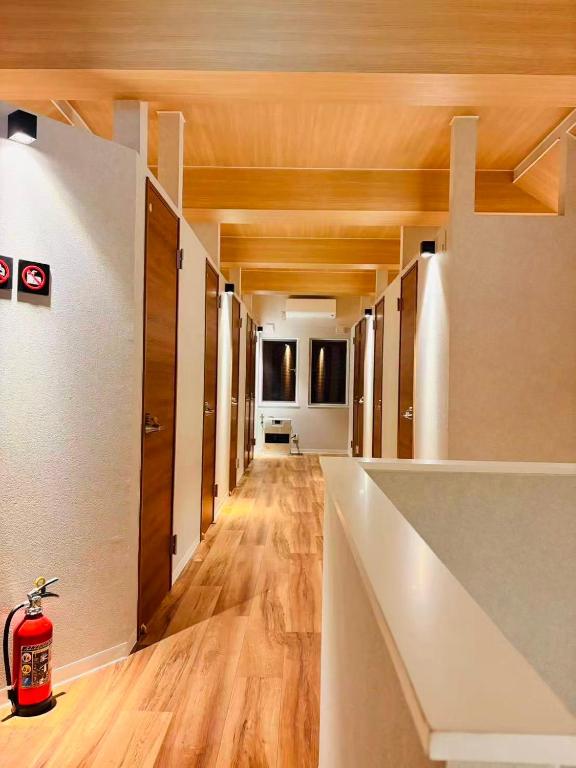 an empty hallway with wood floors and a fire extinguisher at Hitori Otaru in Otaru