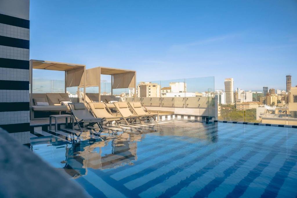 a swimming pool with chairs on the roof of a building at Faranda Collection Barranquilla, a member of Radisson Individuals in Barranquilla