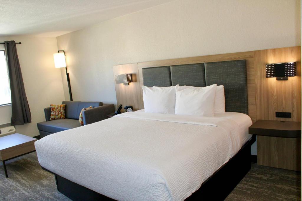 a hotel room with a large bed and a chair at The Cairn Hotel in Cedar City