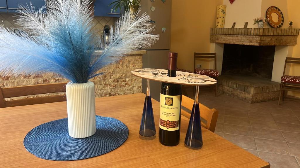 a table with two bottles of wine and a vase with feathers at Galliu'S home in Selargius