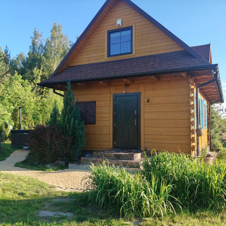 a small wooden house with a black door at Jałowcowe Zacisze in Brody
