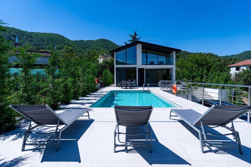 a swimming pool with chairs and a house at BlackPine Villa in Amisianá