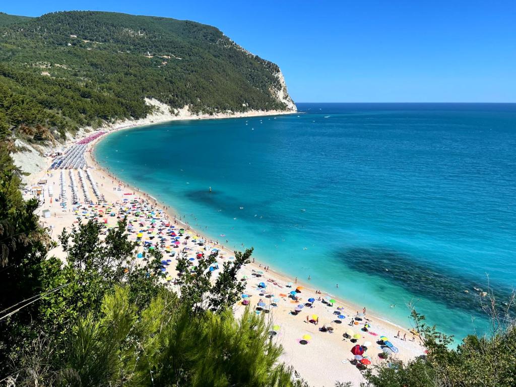 a beach with umbrellas and people in the water at Affittacamere Villa Zelinda in Sirolo