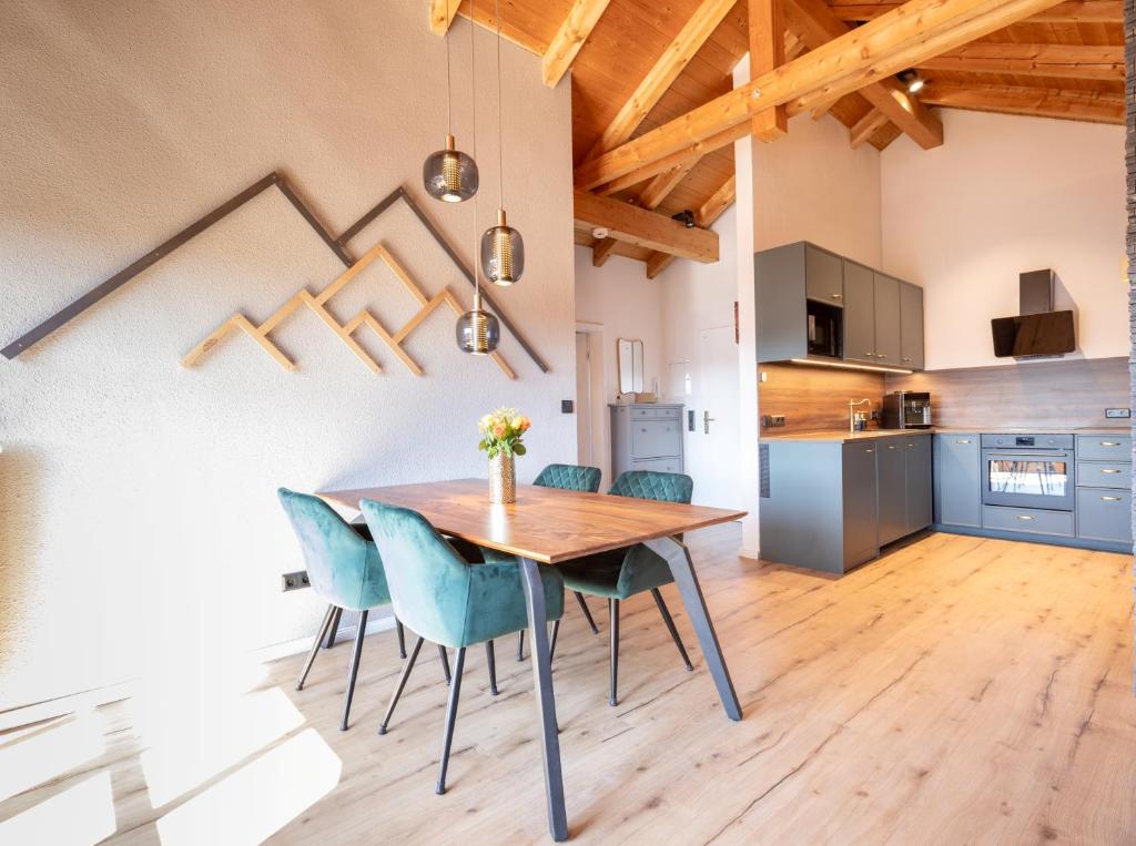 a kitchen and dining room with a wooden table and chairs at Apartment Bergraum - familienfreundlich und zentral in Sankt Englmar