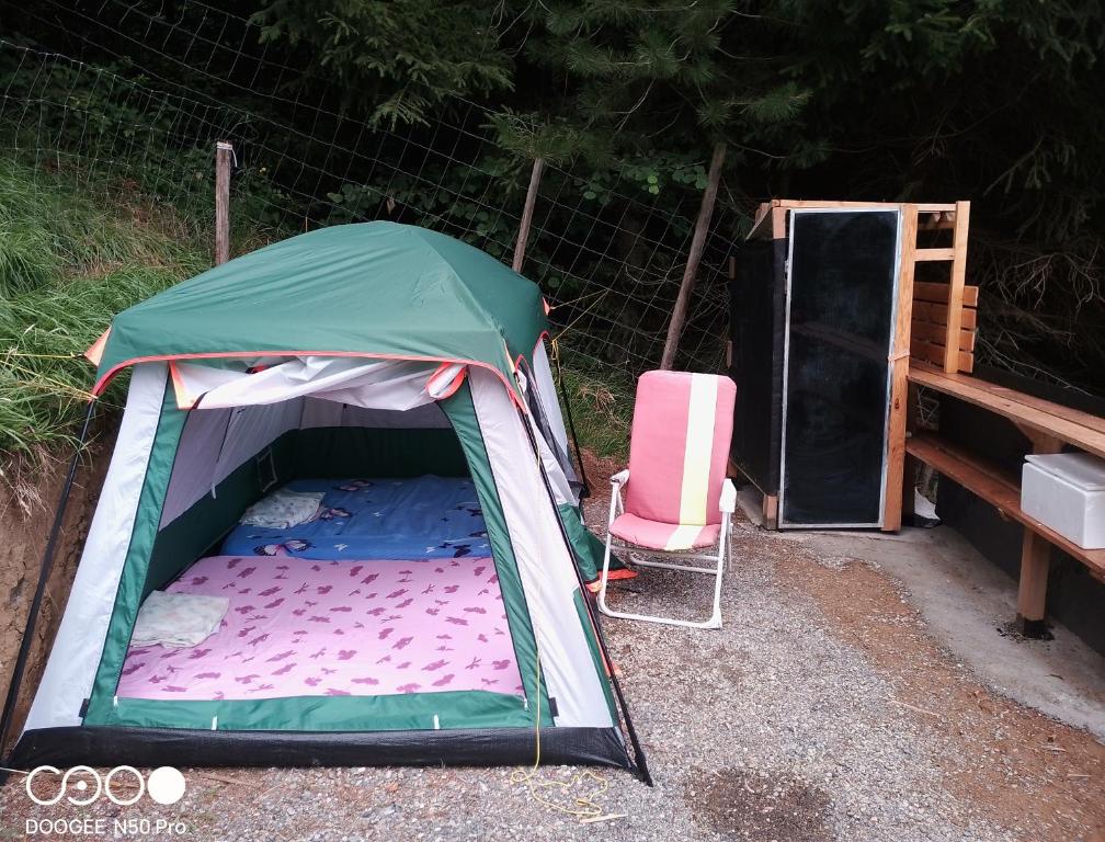a tent and a pink chair in a yard at Tente tout confort in Sarrancolin